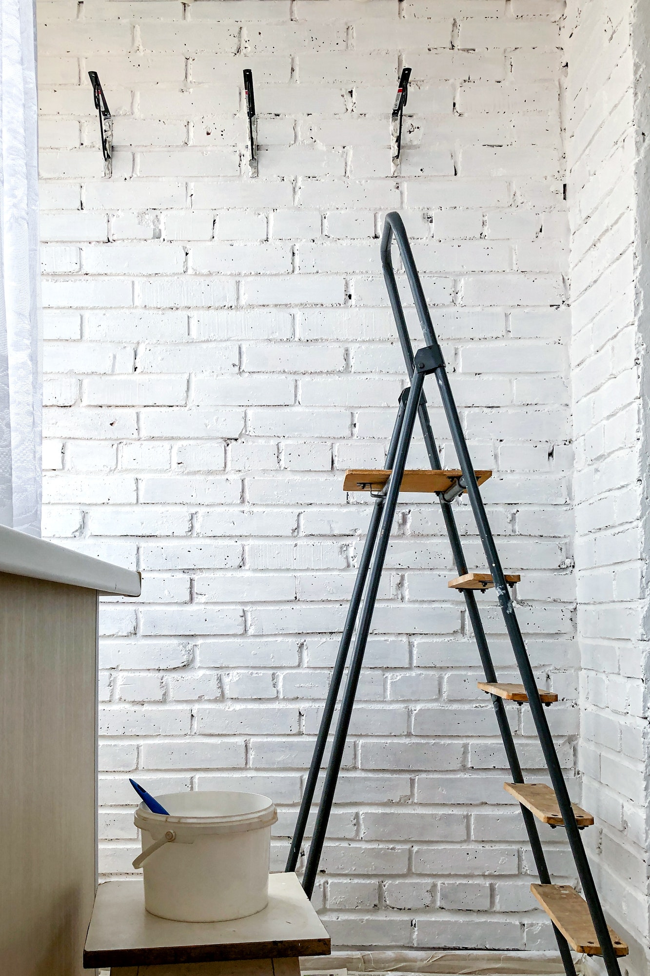 Home renovation. Stepladder stands neat brick wall painted in white